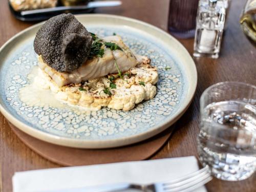 a blue plate with a piece of food on a table at Le Louise Hotel Brussels - MGallery Collection in Brussels