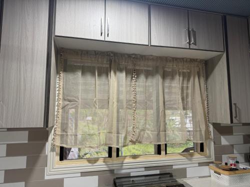 a window in a kitchen with white curtains at Lonely Hill Apartment in Honiara