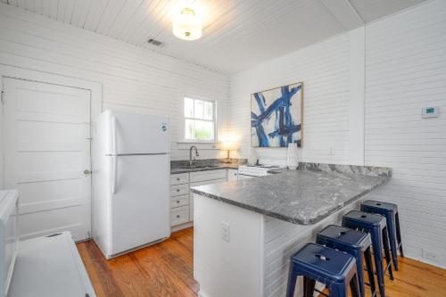 a kitchen with a white refrigerator and blue stools at Shirley Road Cottage by Tybee Cottages in Tybee Island