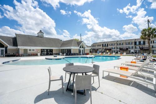 a patio with a table and chairs in front of a pool at Modern Space Great For Extended Stays Pool & Gym in Burnside East