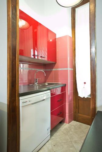 a red kitchen with a sink and red cabinets at Bilocale Nova Milanese vicino Milano Monza - Parcheggio, terrazzo, Wifi, AC, Netfilx - in Nova Milanese