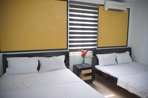 a bedroom with two beds and a vase of flowers at Phố Xưa Central Hotel Hoa Lư - Ninh Bình in Ninh Binh