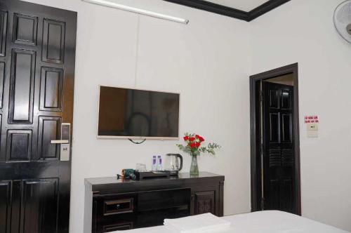 Un dormitorio con una cama y un televisor en la pared. en Khách sạn Phố Xưa, en Ninh Binh