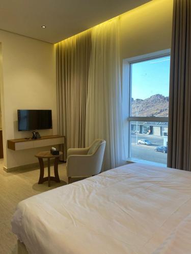 a hotel room with a bed and a chair and a window at شقق نيفا المخدومة in Hail