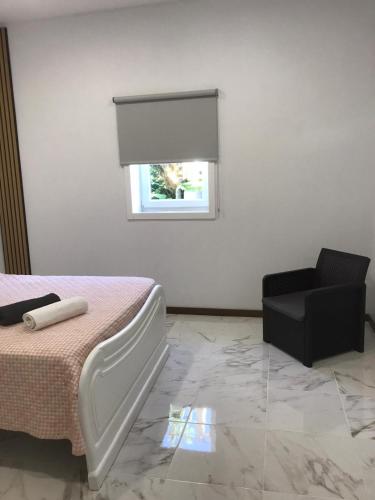 a bedroom with a bed and a chair and a window at Casa de Ferias Tranquilo in Bitarães