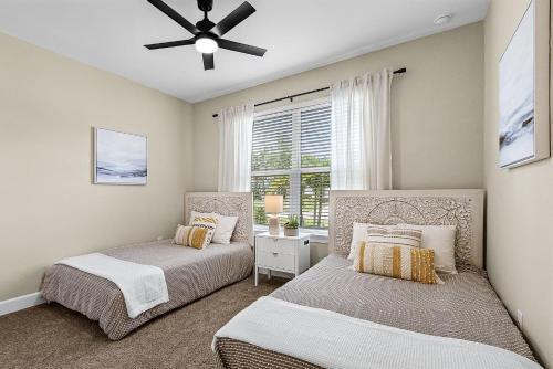 two beds in a bedroom with a ceiling fan at Charming, Comfort and Relaxation Await! - Casa Bella - Roelens in Matlacha