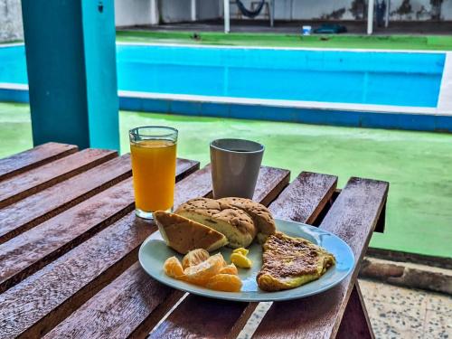 a plate of breakfast food and a glass of orange juice at Palo Verde House in Iquitos