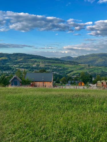 a field with a barn and mountains in the background at Somnium Pieniny in Tylka