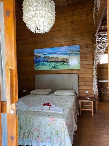a bedroom with a bed with a painting on the wall at Bangalôs Flecheiras de Canaã in Flecheiras