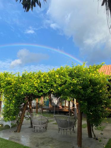 a group of chairs under an orange tree with a rainbow in the sky at Bangalôs Flecheiras de Canaã in Flecheiras