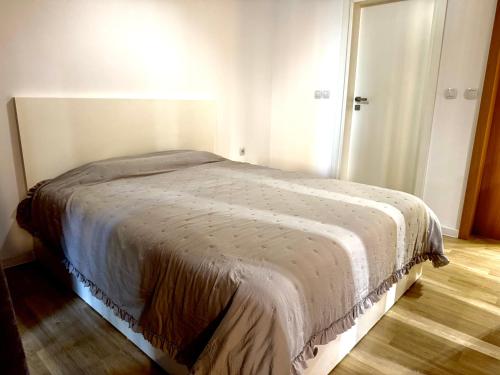 Cama en habitación blanca con suelo de madera en Studio Sredec 77, en Plovdiv