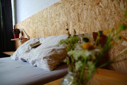 a bed with a pillow and a vase of flowers at Zimmer 3 in Gomadingen