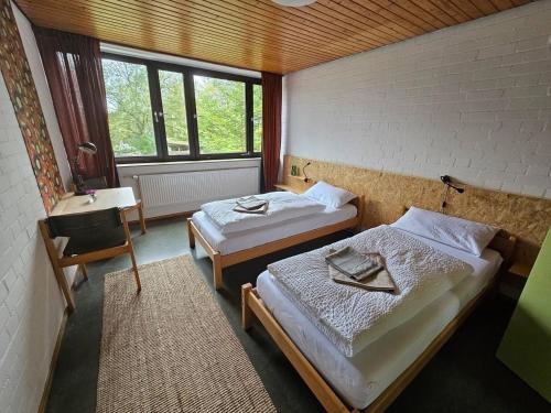 a room with two beds and a desk and window at Zimmer 1 in Gomadingen