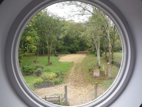 a round window looking into a park with a dirt road at 1 bed in Beaulieu 53042 in Beaulieu
