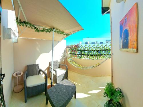 a patio with chairs and an umbrella and a hammock at Modern and cozy apartment in the heart of Kenitra in Kenitra
