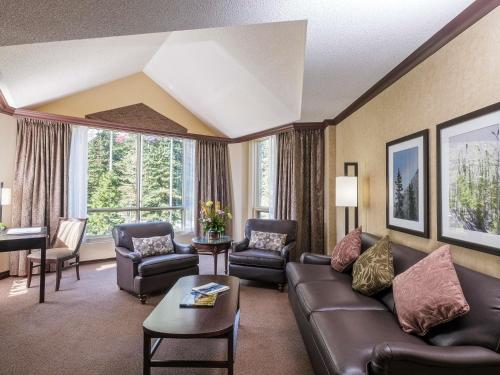 a living room with a leather couch and chairs at Rimrock Banff, Emblems Collection in Banff