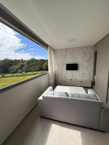 a bedroom with a bed and a large window at Promoção em Bombinhas até 4 pessoas c Piscina Aquecida in Bombinhas