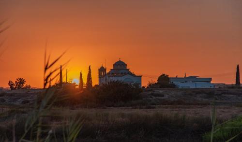 a sunset over a city with buildings in the foreground at TelMar duplex in Livadhia