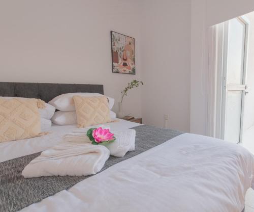a white bed with towels and a flower on it at TelMar duplex in Livadhia