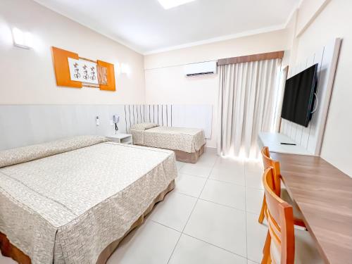 a hotel room with two beds and a flat screen tv at diRoma Spazzio direto com o Grupo diRoma com acesso ao Acqua Park e Café da manhã in Caldas Novas