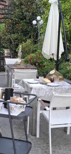 a table with white chairs and an umbrella at B&B Montisclari in Monchiero