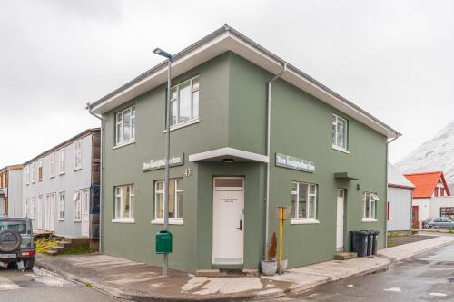 a green building with a white door on a street at The Ísafjörður Inn by Ourhotels in Ísafjörður