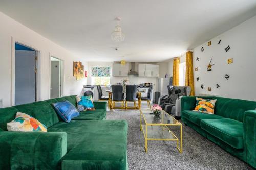 a living room with green couches and a table at F1TR Luxurious & Comfy Stay in Batley