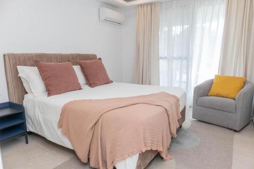 a bedroom with a large bed and a chair at Kololi Sands in Serekunda