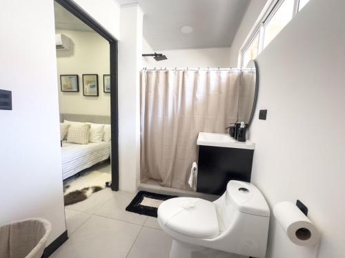 a white bathroom with a toilet and a shower at JJ Lux Residential in Jacó