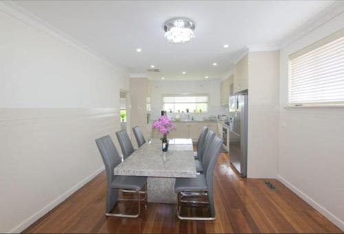 a dining room table with chairs and a vase of flowers at Seffa home stay in Noble Park