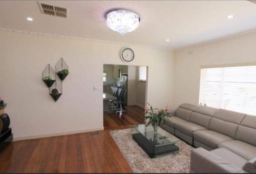 a living room with a couch and a clock on the wall at Seffa home stay in Noble Park