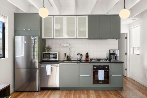 una cucina con armadietti bianchi ed elettrodomestici in acciaio inossidabile di Modern East Austin House by Barcle ad Austin