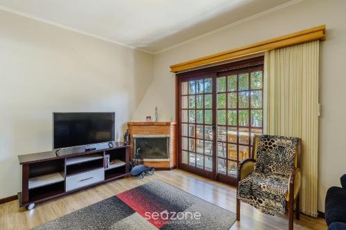 ein Wohnzimmer mit einem TV und einem Kamin in der Unterkunft Apto 300m do lago negro em Gramado/RS RLN0104 in Gramado