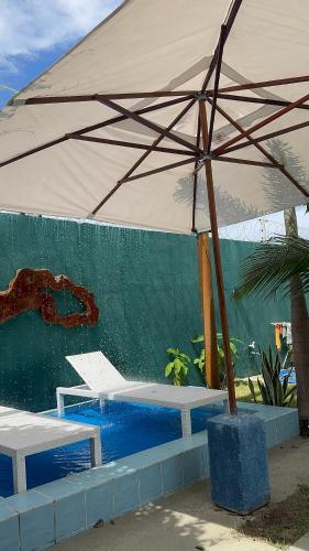 a large umbrella sitting next to a swimming pool at Bangalôs Flecheiras de Canaã in Flecheiras