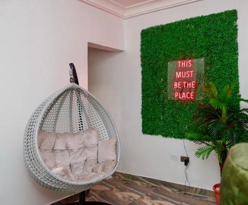 una sedia sospesa in rattan in una stanza con un quadro verde di KUI Space ad Abuja