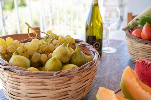 a basket of fruit on a table with a bottle of wine at Terra Ionian in Áyios Ilías