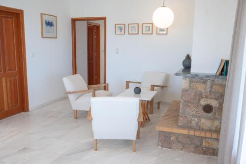 a living room with white chairs and a fireplace at Terra Ionian in Áyios Ilías