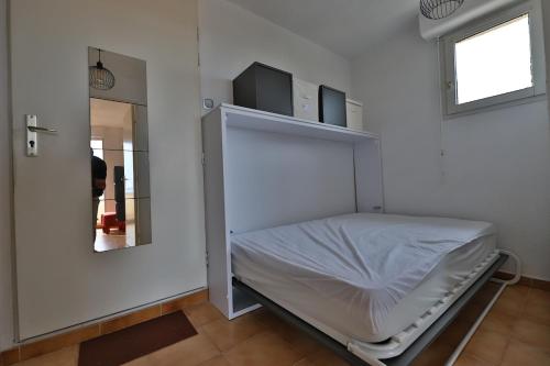 een witte kamer met een bed en een spiegel bij Ciel et mer in Sausset-les-Pins