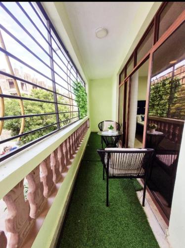 a balcony with a table and chairs and windows at CaLITWAPA APPARTMENTS in Mtwapa