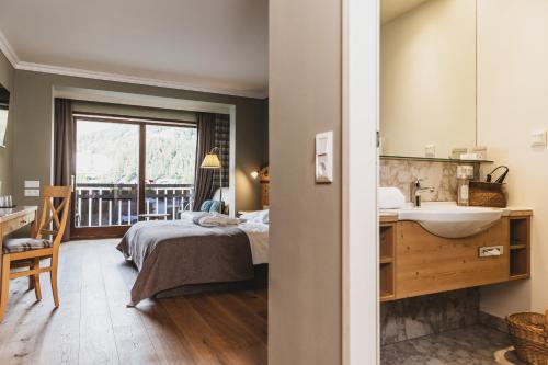 a bedroom with a bed and a sink and a window at Seehotel Jägerwirt in Turracher Hohe