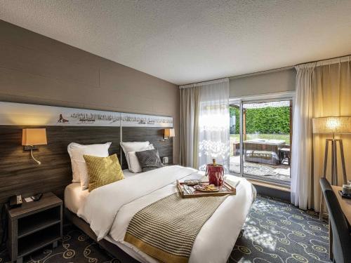 a hotel room with a large bed and a balcony at Mercure Annecy Sud in Annecy