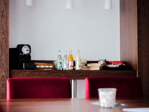 a table with two chairs and bottles on a counter at Mercure Annemasse Porte De Genève in Gaillard