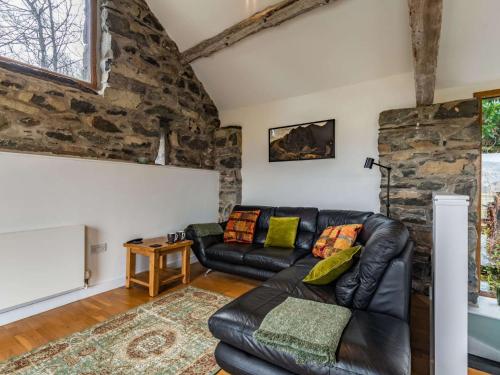 a living room with a leather couch and a stone wall at 2 bed in Arthog 66611 in Arthog