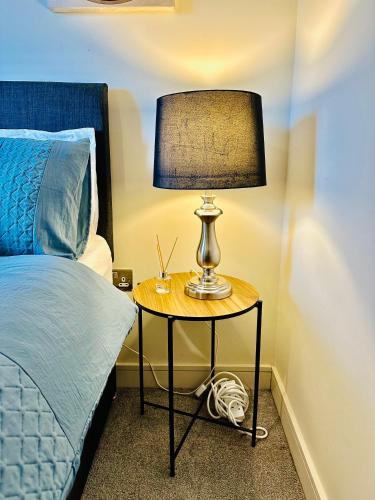 a lamp on a table next to a bed at Spacious Room in Cardiff Bay Apartment with Private Bathroom in Cardiff