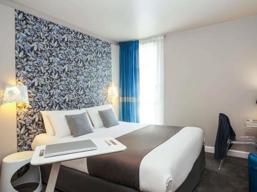 a hotel room with a bed with a laptop on it at Mercure Le Mans Batignolles - Hotel & Spa in Le Mans