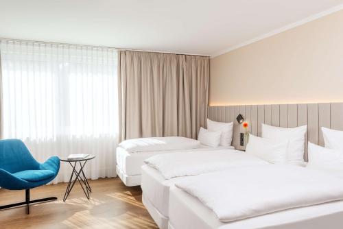 a hotel room with two beds and a blue chair at NH Köln Altstadt in Cologne