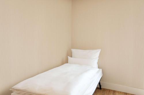 a white bed in a corner of a room at NH Köln Altstadt in Cologne