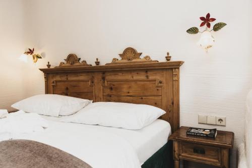 a bedroom with a bed with a wooden headboard and a table at Seehotel Jägerwirt in Turracher Hohe