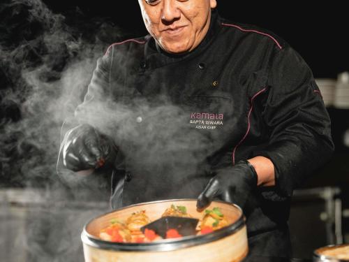a man is stirring a pot of food with smoke at Sofitel Cairo Downtown Nile in Cairo