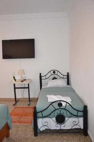 a bedroom with a bed and a tv on a wall at La Belle Vue Guest House in Aït Ben Haddou